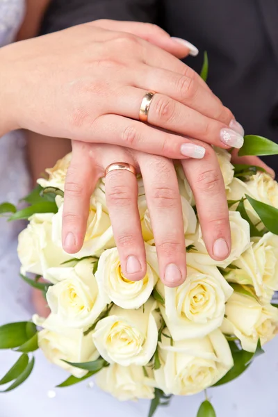 Händer med bröllop ringar på ett bröllop bukett — Stockfoto