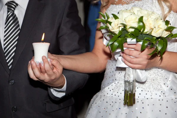 Горящая свеча в руках жениха и невесты — стоковое фото