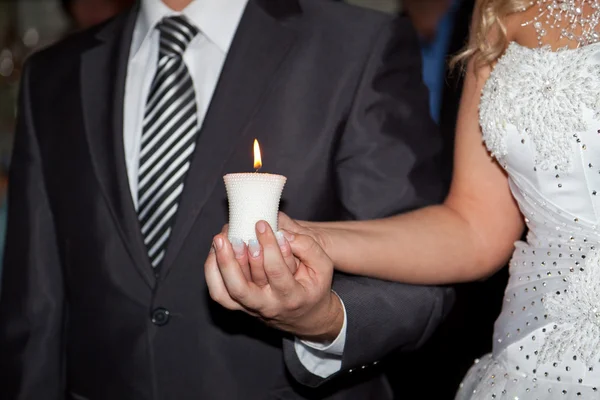 Brandende kaars in handen van de bruidegom en de bruid — Stockfoto