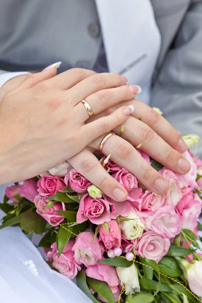 Händerna på brudgummen och bruden på ett bröllop bukett — Stockfoto