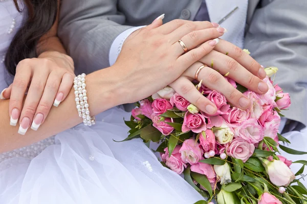 Mains du marié et de la mariée sur un bouquet de mariage — Photo