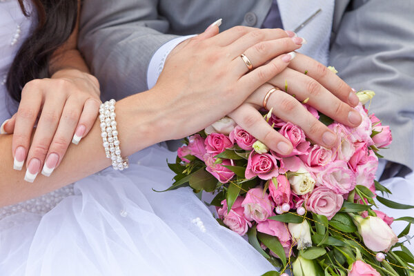 Hands of the groom and the bride on a wedding bouquet