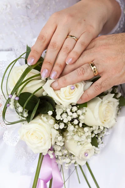 Mãos com anéis de casamento em um buquê — Fotografia de Stock