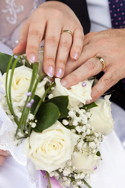 Hände mit Eheringen an einem Strauß — Stockfoto