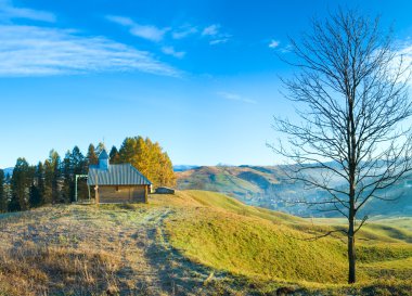 Wooden chapel on autumn mountain top clipart