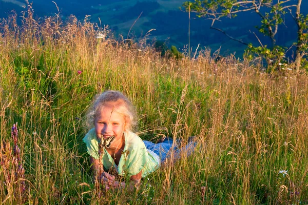 Девушка и бабочка на горных травах — стоковое фото