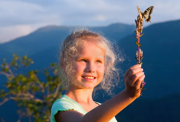 Kislány és a pillangó a naplemente-hegy — Stock Fotó