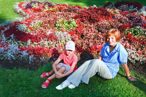 Mãe com doughter perto de canteiro de flores — Fotografia de Stock