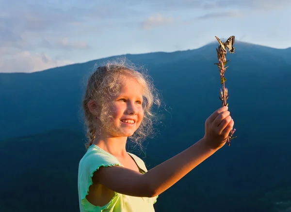 Mädchen und Schmetterling im Sonnenuntergang Berg — Stockfoto