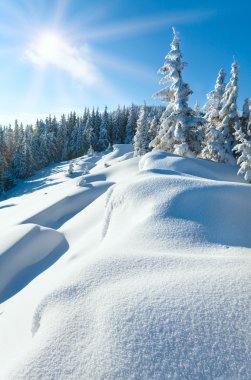 Snowdrifts on winter snow covered mountainside and sun clipart