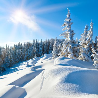 Snowdrifts on winter snow covered mountainside and sun clipart