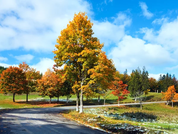 Primeiro inverno neve e outono folhagem colorida perto da estrada da montanha — Fotografia de Stock