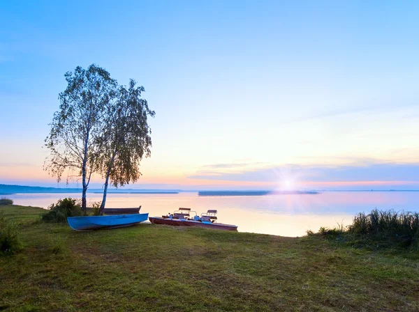 Захід сонця з човнами біля берега літнього озера — стокове фото