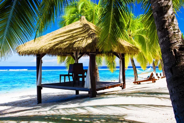 Tropischer Pavillon mit Liegestühlen am Strand mit Palmen — Stockfoto