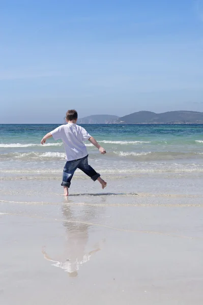 Szardínia, kisfiú játszik egy fehér homokos alghero tengerparton, — Stock Fotó