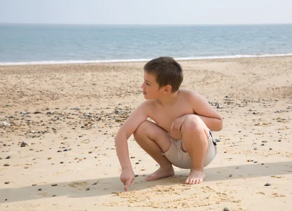 年轻的男孩在沙子里绘制图片 — 图库照片