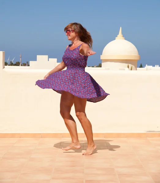 Age doesn't matter - tanned, fit middle-aged woman dances on the — Stock Photo, Image