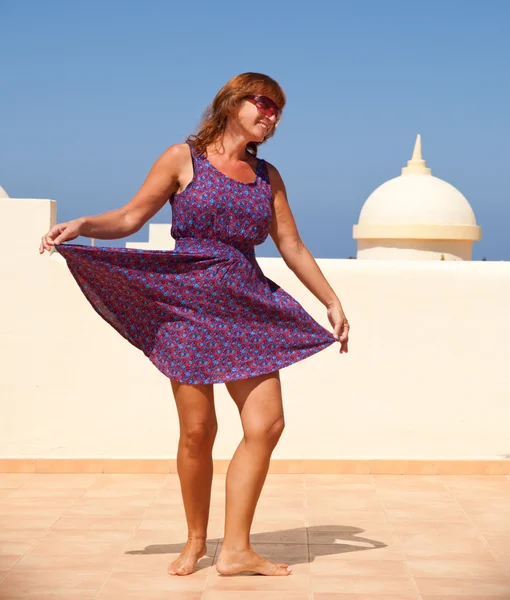 Age doesn't matter - tanned, fit middle-aged woman dances on the — Stock Photo, Image