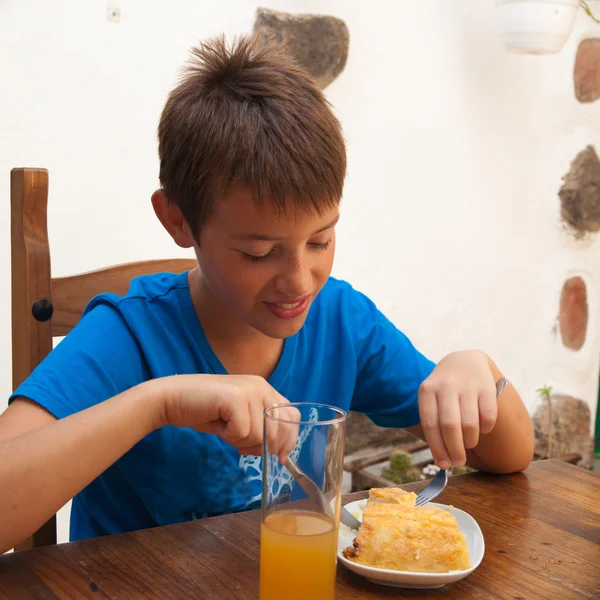 Tanned caucasian boy eating a portion of tortilla in a cafe — Stock Photo, Image