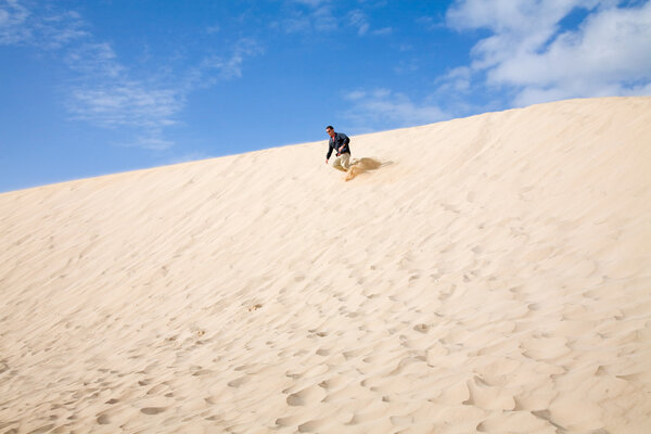 Man running downhill in the dunes of Corralejo