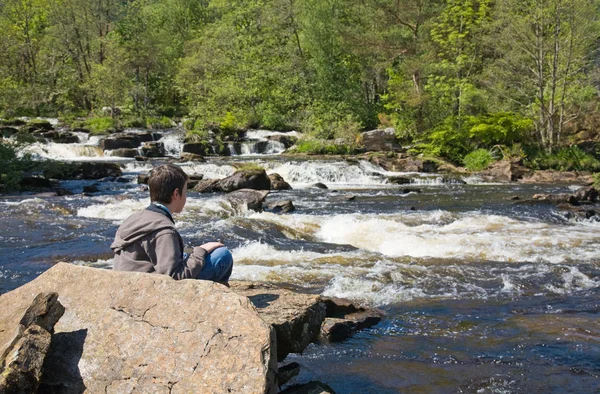 Jongen op zoek naar water rapids (de watervallen van dochart, scotlan — Stockfoto