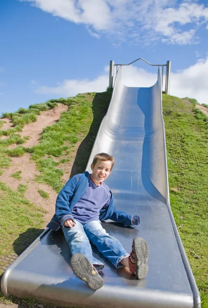 Little boy sliding down playground slide, some motion blur — Stock Photo, Image