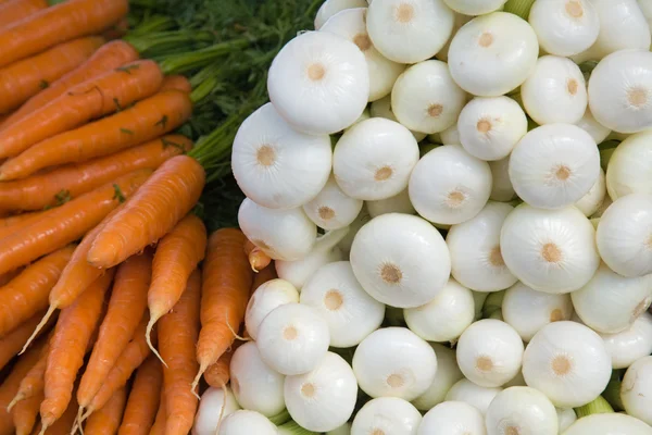 Friss fiatal fehér hagyma és a sárgarépa, a piactér, háttér — Stock Fotó