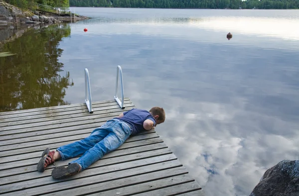What's there? (little boy laying on his tummy on a old wooden pi — Stock Photo, Image