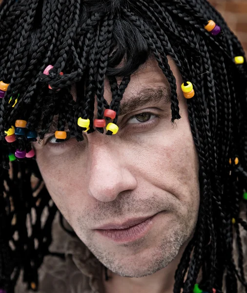Kaukasischer Typ in einer Party-Perücke mit vielen Zöpfen und Perlen — Stockfoto