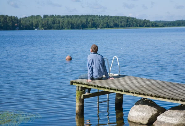 stock image Man sunning himself at the end of old wooden pier