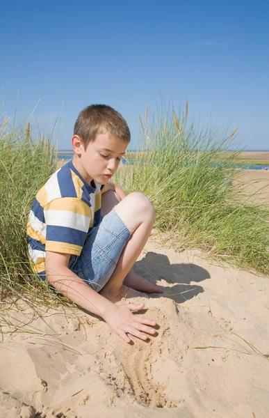 Χαριτωμένο μικρό αγόρι που παίζει με την άμμο στους αμμόλοφους, δίπλα στη θάλασσα — Φωτογραφία Αρχείου