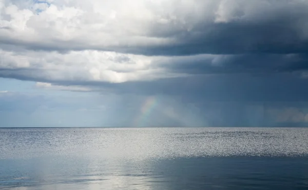 Rain clouds and rainbow over northern sea — Stock Photo, Image