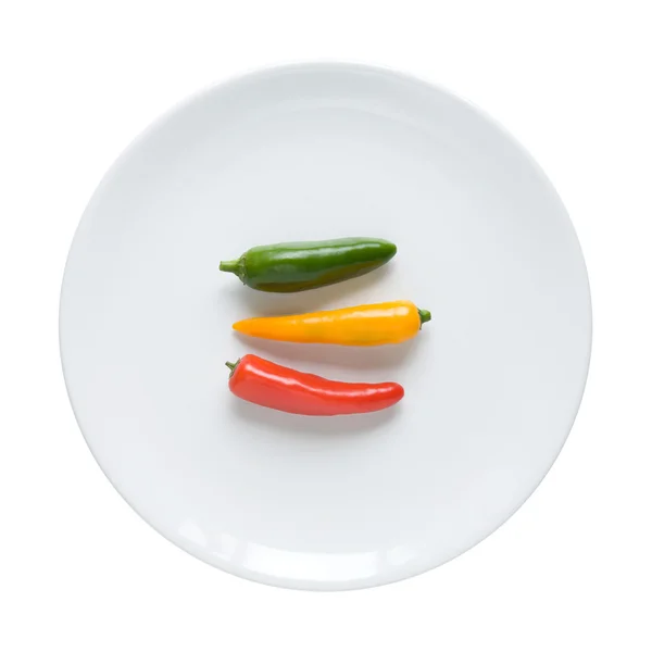 Traffic light chilly pepper on round white dinner plate — Stock Photo, Image