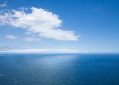 View over the ocean far below; white clouds and its reflection clipart