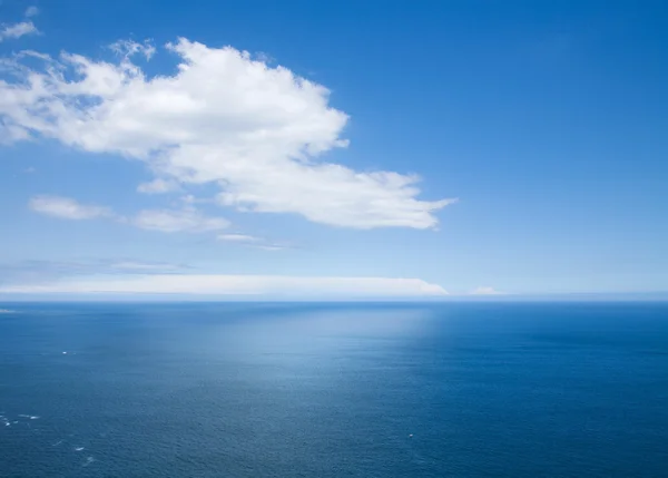 View over the ocean far below; white clouds and its reflection — Stock Photo, Image