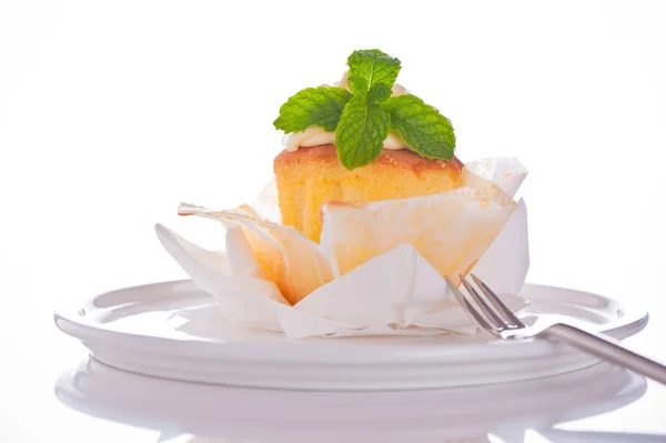 Cupcake con crema de vainilla y hoja de menta sobre fondo blanco —  Fotos de Stock