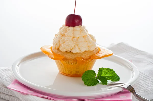Una magdalena en una taza de caramelo con crema de vainilla sobre fondo blanco —  Fotos de Stock