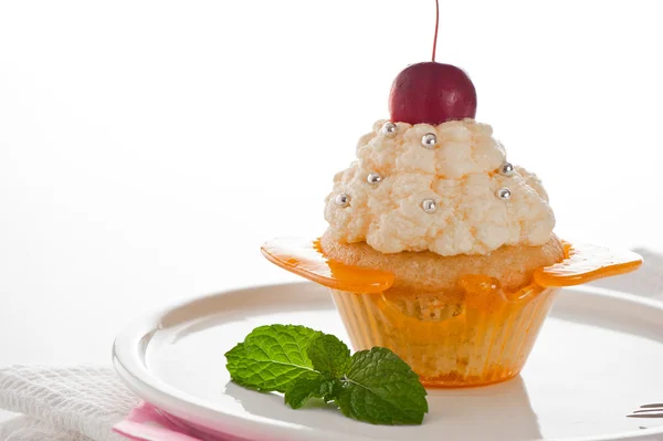 Una magdalena en una taza de caramelo con crema de vainilla sobre fondo blanco —  Fotos de Stock