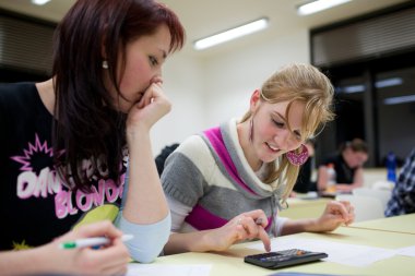 Pretty female college student sitting in a classroom full of stu clipart