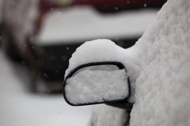 Cars parked on a city street covered with snow after a heavy sno clipart