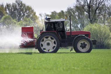 Tractor spraying a filed with pesticides/fertilizers clipart