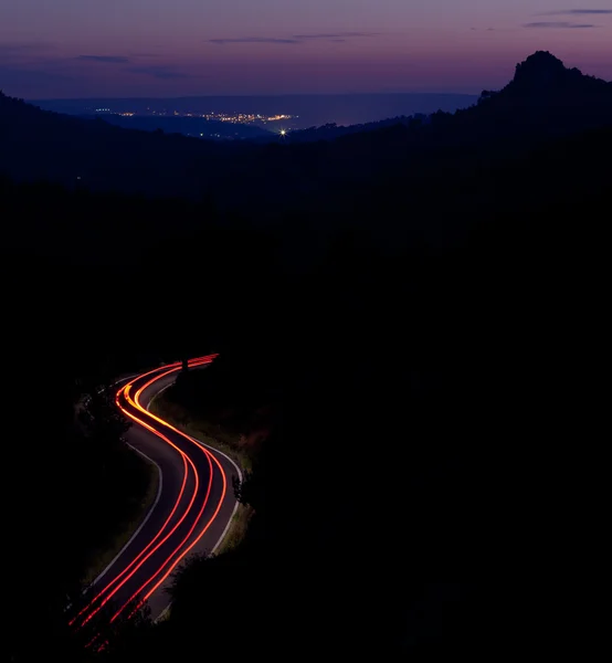 Carro em movimento rápido em uma estrada sinuosa ao entardecer — Fotografia de Stock