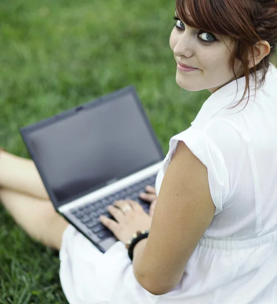 Красивая молодая женщина, работающая за компьютером на открытом воздухе, смотрит — стоковое фото