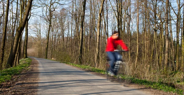 Bikers on a biking path in a park (motion blur is used to convey — Stock Photo, Image