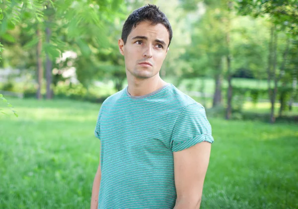 Portret van een knappe jongeman terwijl buiten in een park op een l — Stockfoto