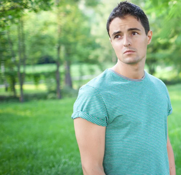 Porträtt av en stilig ung man samtidigt utomhus i en park på en l — Stockfoto