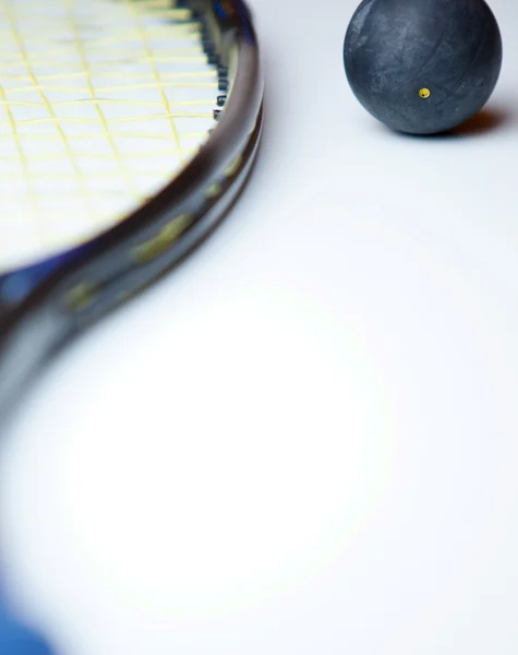 Bola de squash e uma raquete de squash no fundo branco — Fotografia de Stock