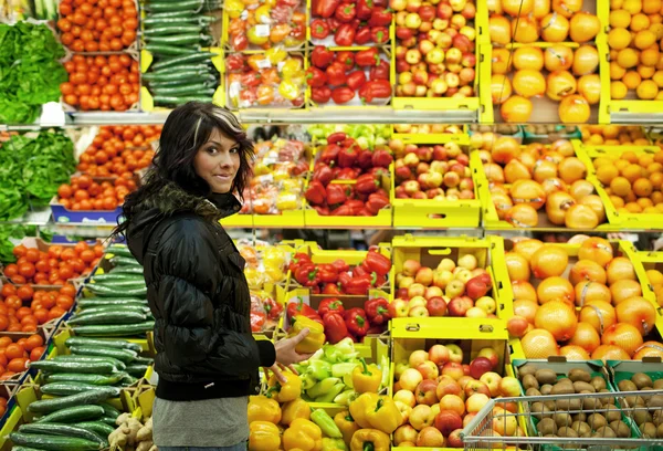 Красива молода жінка купує фрукти та овочі в супермарці — стокове фото