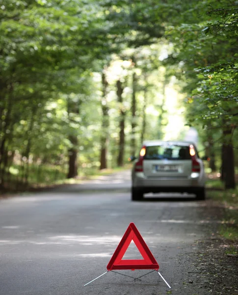 Roto coche con triángulo de advertencia detrás de él esperando assi —  Fotos de Stock