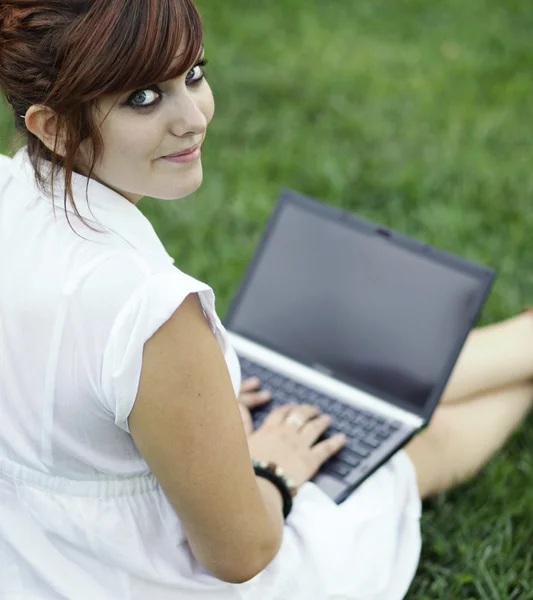 Mooie jonge vrouw die werkt op een laptopcomputer buitenshuis, lookin — Stockfoto